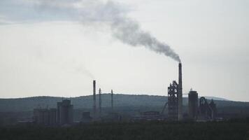 Lavorando fabbrica con un' fumo tubo nel foreste la zona. azione filmato. energia stazione o energia pianta visto a partire dal lontano lontano sopra foresta con fumo camino, inquinamento di il ambiente concetto. video