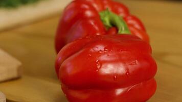 Close-up of two red ripe sweet peppers. Stock footage. Beautiful juicy sweet peppers lie before slicing on wooden background. Juicy ripe vegetables video