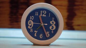 cerca arriba de raro alarma reloj de azul color con blanco marco. concepto. azul alarma reloj con blanco números y metal manos en pie en el mesa en el habitación. video