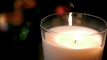 Close-up of festive candle on background of blurred lights. Concept. Clear focus on candle holder burning on background of festive colorful blurred lights video