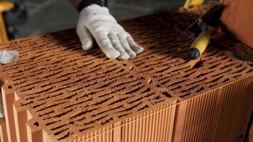 Industrial bricklayer worker placing bricks on cement while building walls. Stock footage. Close up of a man in protective gloves putting heavy brick block to form a layer. video