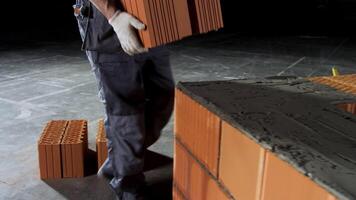 Industrial bricklayer worker placing bricks on cement while building walls. Stock footage. Close up of a man in protective gloves putting heavy brick block to form a layer. video