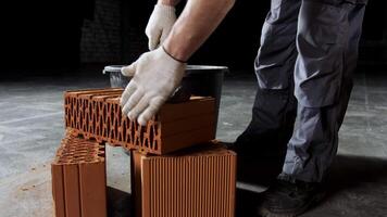 Close up of an industrial worker putting cement on the brick for construction work. Stock footage. Hands of a man putting mortar on red brick, materials and construction concept. video