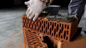 Close up of an industrial worker putting cement on the brick for construction work. Stock footage. Hands of a man putting mortar on red brick, materials and construction concept. video