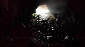 View from inside a cave with rocky path and daylight at the entrance. Stock footage. Unknown underground tunnel, dangerous travel concept. video