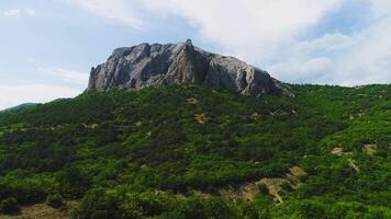 Top view of steep rocky slopes at top of green mountain on background of sky. Shot. Beautiful rocky top of picturesque green mountains video