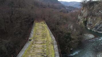 Antenne von bergig Landschaft von alt verlassen Stein Brücke Über kalt Strom in der Nähe von steil Klippen. Schuss. fliegend Über das Brücke führen nirgends. video