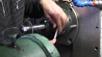 Mechanic repairman at the factory adjusting the machine with large and heavy key, holding it with both hands. Stock footage. Close up of machinery and professional equipment. video