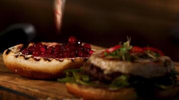 caseiro grade carne hamburguer ou sanduíche com queijo Camembert queijo, oxicoco molho e bagas, fresco verde mostarda brotos. estoque imagens de vídeo. a perfeito almoço do ocidental cozinha, pornografia alimentar. video