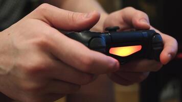 Close-up of man's hands holding a remote control from a game console and playing video games. Concept. Weekends and recreation