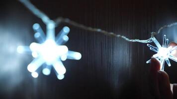 Close-up of woman's hand touching the beautiful electric Christmas garland of bright lights hanging on the wooden wardrobe or door. Concept. Christmas mood video