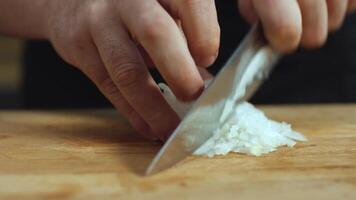 Close-up of man hands cutting white onions on a wooden chopping board with a kitchen knife. Stock footage. Preparing food. video