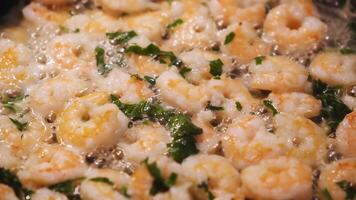 Close-up of fresh shrimps with basil fried in oil on a frying pan. Concept. Delicious seafood video