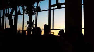 Close-up of people silhouettes standing in the dark room near the window at the sunset. Concept. Evening observation platform video