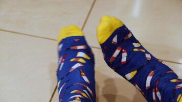 Close-up of man's legs in funny blue and yellow socks with printed bottles of wines. Concept. Cozy home clothes video