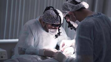 Surgeons perform operation under anesthesia. Action. Two professional surgeons are working hard to remove or treat disease. Surgery and operation video