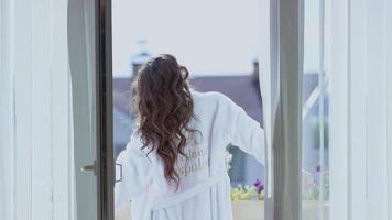 Attractive woman stretch on balcony. Video. Back view of beautiful woman in white coat stretching on balcony on sunny morning. Attractive woman on vacation abroad video