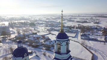 de cerca ver en el azul domos y dorado cruces de el ruso ortodoxo Iglesia cerca el pequeño pueblo en claro invierno día. disparo. religión y fe video