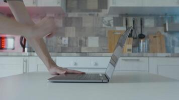 Hands open laptop on kitchen. Action. Young man opens laptop at kitchen table. Student is resting on laptop at home. Modern stylish and inexpensive laptop video