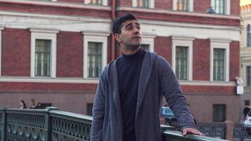 Handsome male tourist enjoing architecture. Media. Side view of carefree young man standing and thinking about something in the street on the background of driving cars. video