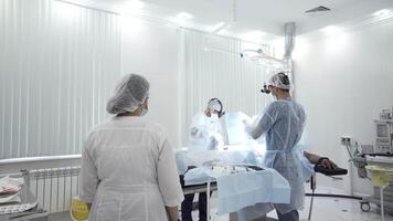 Team of doctors perform surgery while patient is under anesthesia. Action. View inside of the operating room with men surgeons, nurse, and sedated male patient. video