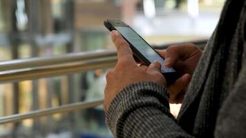 cerca arriba de hombre manos mensajes de texto un mensaje en compras centro comercial antecedentes. medios de comunicación. masculino manos utilizando su teléfono inteligente para chateando en social neto. video