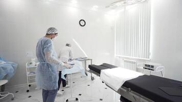 Man and woman medical doctors in the procedure room. Action. Nurse and the surgeon preparing surgical instruments and tools including scalpels, forceps and tweezers arranged on a table. video