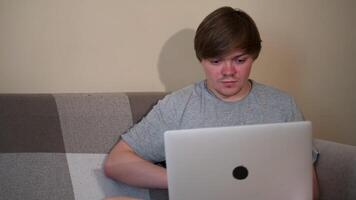 Relaxed serious guy student or freelancer using laptop device on sofa at home. Concept. focused entrepreneur working distantly looking at notebook in apartment. video