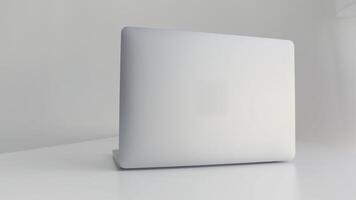 bak- se av en vit bärbar dator isolerat på vit bakgrund. handling. modern smal design av en ny bärbar dator tillverkad av aluminium material på vit tabell, begrepp av modern teknik. video