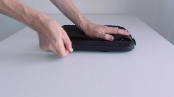 Mens hand- zetten laptop in een geval, zippen het omhoog en nemen weg van de tafel. actie. dichtbij omhoog van mannetje hand- plaatsen modern portable computer in de bage en nemen het weg. video