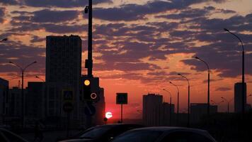 brillante naranja puesta de sol terminado el ciudad en el noche. brillante puesta de sol y siluetas de alto subir edificio y casas en el ciudad calle, verano noche. video