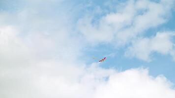 cometa volador en el cielo entre el nubes concepto. fondo ver de el verano azul cielo con blanco nubes y altísimo arco iris vistoso cometa, concepto de libertad y infancia. video