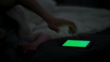 giovane uomo dipendente per smartphone con verde schermo nel letto a notte. concetto. vicino su di uomo sofferenza a partire dal insonnia utilizzando il suo smartphone con croma chiave mentre dire bugie nel il suo letto a notte. video