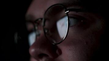 Glasses with reflected computer screen in lenses. Concept. Close up of thoughtful business man face or focused student working late at night isolated on black background. video