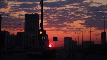 temprano Mañana amanecer en un ciudad calle. concepto. asombroso rosado y naranja cielo con brillante rojo brillante Dom creciente encima el oscuro ciudad con caminando personas y conducción carros. video