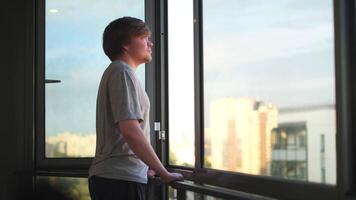 Happy man at home balcony looking far in the distance through an opened window. Concept. Side view of a young blond man enjoying the urban view. video