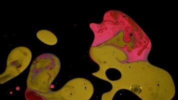 Liquid paint texture in slow motion isolated on black background. Stock footage. Artistic background with mixing of bright colors on black surface, fluid art concept. video