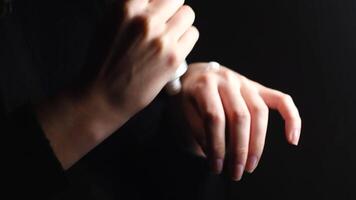 Woman using moisturizing cream to prevent dry skin of her hands. Concept. Close up of tender female hands applying some white lotion on her hands isolated on black background. video