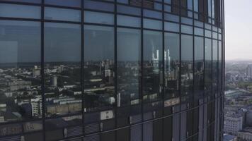 schließen oben von Glas Fenster von ein Wolkenkratzer und das Stadtbild hinter Es. Lager Filmaufnahme. Antenne Aussicht von das modern hoch erhebt euch Geschäft Center und das Stadt mit ein Fluss. video