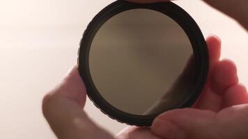 Photographic camera equipment filter isolated on white background. Concept. Female hands demonstrating the effect of polarizing filter for camera lens. video