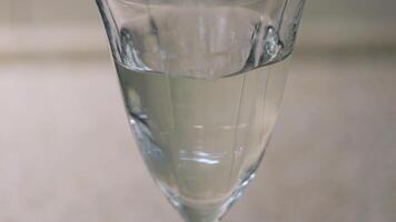 Close up of drops of liquid vitamins falling down into the clear water in a glass. Concept. Taking vitamins during coronavirus covid 19 pandemic, prevention of disease. video