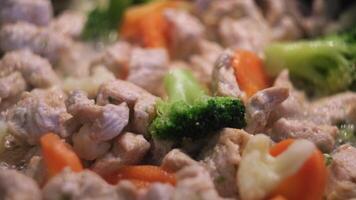 Stir fry chicken with vegetables, healthy food and diet. Concept. Close up of frying green broccoli, carrots, and chicken in boiling sunflower oil. video