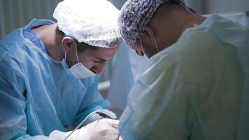 Close-up of professional surgeons performing surgery on person. Action. Two specialized surgeons carefully perform operation under anesthesia video