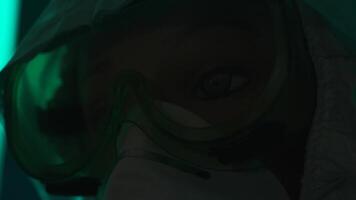 Details of a quest game in epidemic theme. Stock footage. Close up of a face of a manikin in a mask and protective suit in a dark room with dim light. video