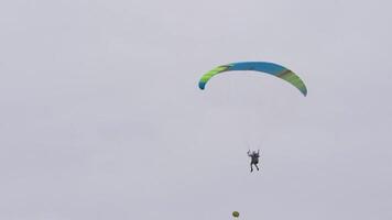 Bottom view of man with parachute in sky. Action. Person flies in sky on paraglider in cloudy weather. Extreme sports and skydiving video