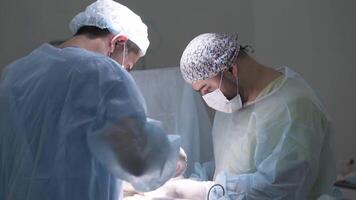 Surgeons operate on person under anesthesia. Action. Two professional surgeons make incisions to patient under anesthesia. Concentrated faces of surgeons during operation video