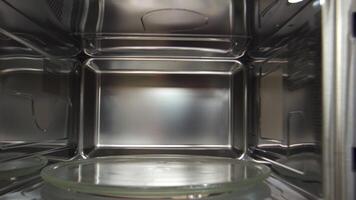 View inside of microwave oven, concept of cooking and technologies. Household utensils. Close up of empty microwave turntable glass tray inside of the microwave oven. video