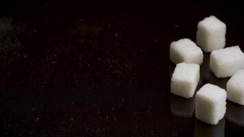 Close up of hand brushing the half of sugar cubes off the table, giving up on eating candy and sweets. Stock footage. Pieces of white sugar isolated on black background. video