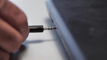 Headphone wire inserted into laptop. Media. Close-up of man inserting wire with headphone connector into laptop. Connecting headphones to laptop via wire video