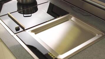 une fraîchement nettoyé verre surface de un électrique cuisinier construit dans le cuisine plan de travail. Ménage ustensiles. proche en haut vue de haute technologie cuisine détails. video